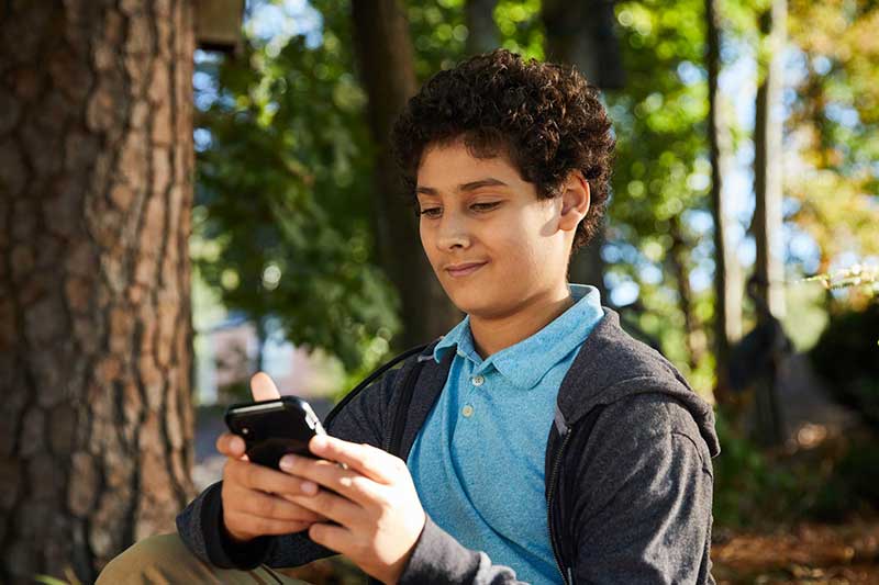 boy checking social media outside